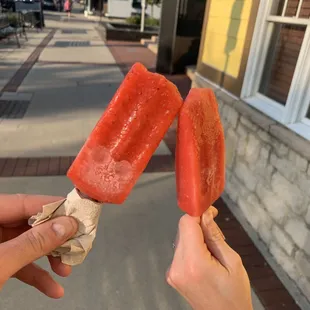 two hands holding two pops