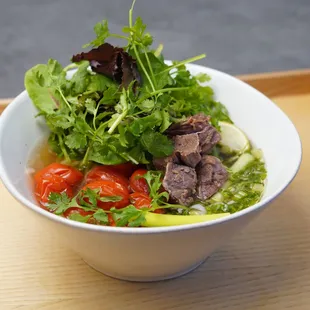 Tomato Beef Pho: Rice noodles soup with 12 hrs braised beef oxtails, diced tomato, mixed leaf, and cilantro.