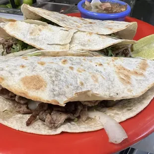 Tacos de harina con carne asada, cilantro y cebolla, con frijoles charros