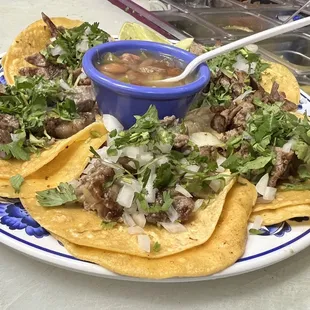 Taquitos de carne asada, con cilantro y cebolla y unos frijoles charros