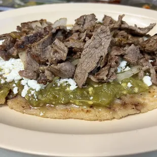 Huarache de carne asada, con salsa verde, queso fresco, cebolla y frijoles (los frijoles están dentro de la tortilla.