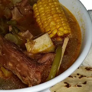 a bowl of beef stew with corn and potatoes