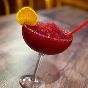 a red drink with a slice of lemon