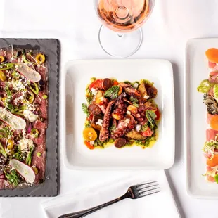 three plates of food and a glass of wine