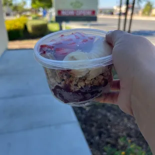 a hand holding a bowl of fruit