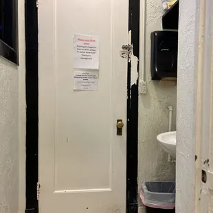 a bathroom door with a sign on it