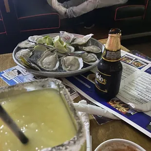 a person sitting in a booth with a bottle of beer and a plate of oysters