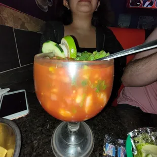 a woman sitting at a table with a cocktail