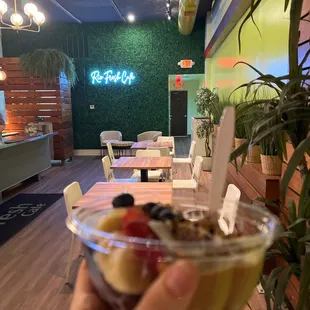 a hand holding a bowl of fruit