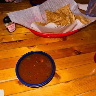 a bowl of salsa and a basket of tortillas