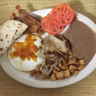 Chuleta (pork chop), eggs, beans, potatoes, side of bacon, tomatoes, onions &amp; fresh tortillas.