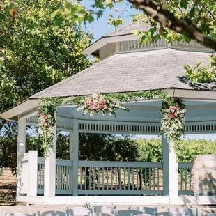 a gazebo surrounded by white chairs