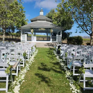 a gazebo surrounded by white chairs