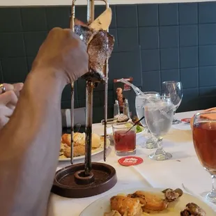 a person holding a knife and fork over a plate of food