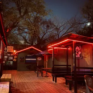 a wooden deck with benches and tables lit up at night