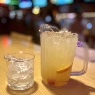 a pitcher of lemonade and a glass of ice