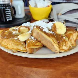 a plate of french toast with bananas and powdered sugar