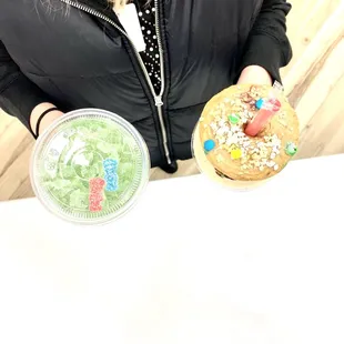 a woman holding a donut and a drink