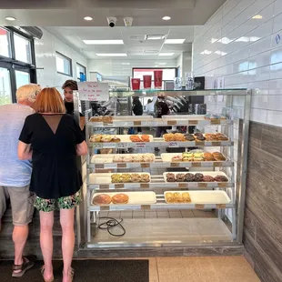 a man and a woman standing in front of a display case of pastries