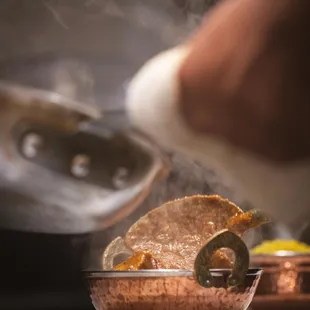 a person cooking food in a copper bowl