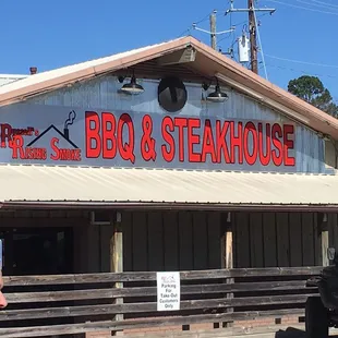 a man standing in front of a bbq and steakhouse