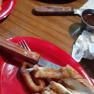 a red plate with onion rings and french fries