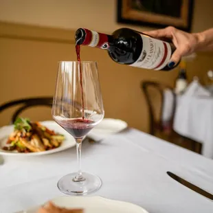 a person pouring wine into a glass