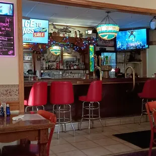 a bar with red chairs and neon signs