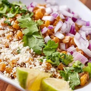 a white bowl filled with rice, beans, cilantro, and lime wedges