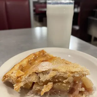a slice of apple pie with a glass of milk