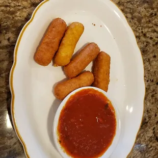 a plate of deep fried donuts and a bowl of ketchup