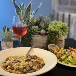 two plates of food and a glass of wine