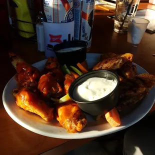a plate of chicken wings, carrots, and ranch dip