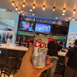 a hand holding a can of coca light