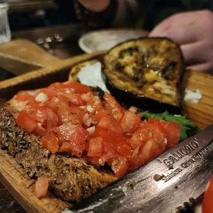 a slice of bread with tomatoes and a knife