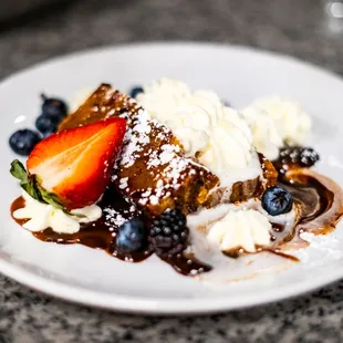 a plate of dessert with strawberries, blueberries, and ice cream