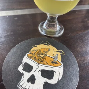 a glass of beer and a skull coaster