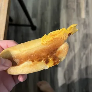 Sausage and cheese kolache with some hardened crusty cheese on outside.