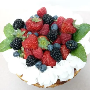 a close up of a cake with berries and whipped cream