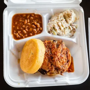a pulled pork sandwich with beans and coleslaw