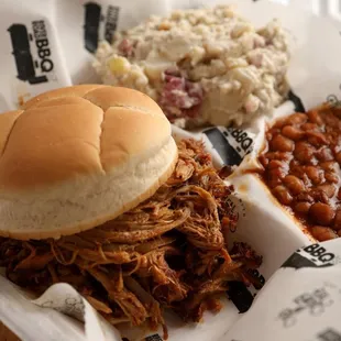 a pulled pork sandwich, beans, and coleslaw