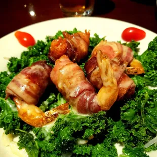 Bacon wrapped prawns on bed of kale.