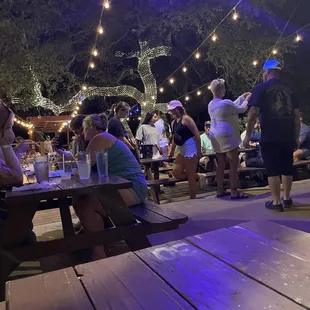 people sitting at picnic tables under string lights