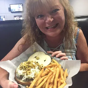 a woman sitting at a table with a sandwich and french fries