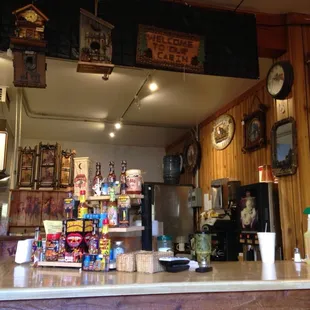 a bar counter with clocks hanging from the ceiling