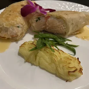 a plate of food that includes a roll, potatoes, and a flower
