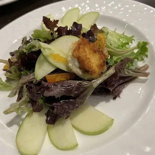 a plate of salad with apples and croutons