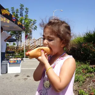 a little girl eating a hot dog