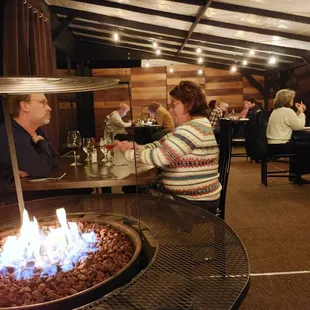 a man and a woman sitting at a table in front of a fire pit