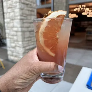 a hand holding a glass of orange juice